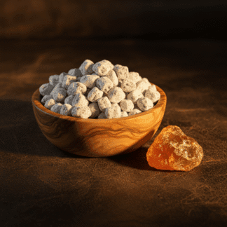 A polished olive wood bowl of handcrafted Amber incense, resting on aged leather next to a piece of raw, golden amber resin.