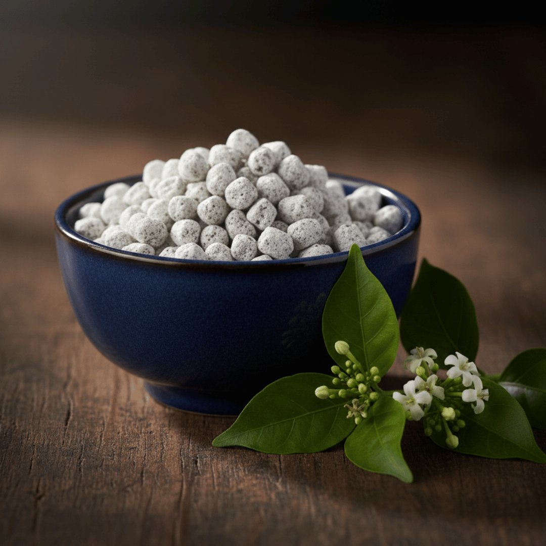 A dark ceramic bowl filled with Night Flower Incense sits on a dark wooden surface, along with a fresh sprig of night flowers.