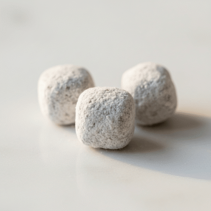 An extreme macro shot of hand-cut Rose incense pieces, highlighting their texture and magnesia coating on a smooth white surface.