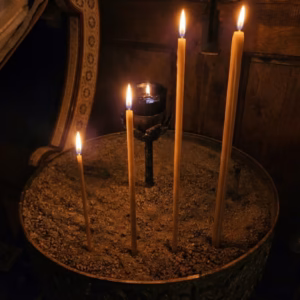 candles-burning-at-vigil Four handmade beeswax candles burning in a sand candle stand in our church. Sizes range from small taper to large pillar.