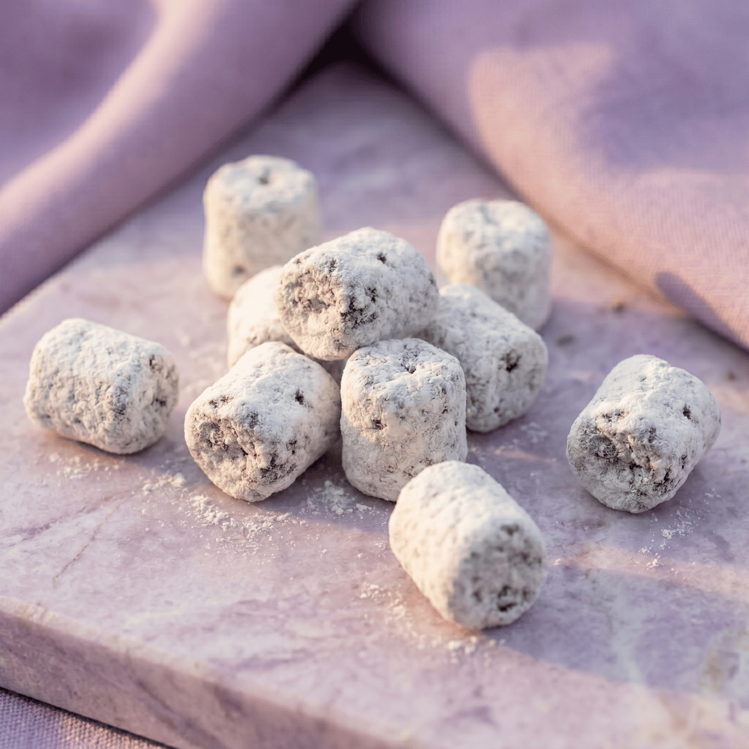 A close up shot of some pieces of Parma Lilac Incense arranged ona marble surface in front of lilac colored drapes.