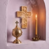 Parma Lilac Athonite Incense burning in front of an ornate wall cross next to a lit beeswax taper.
